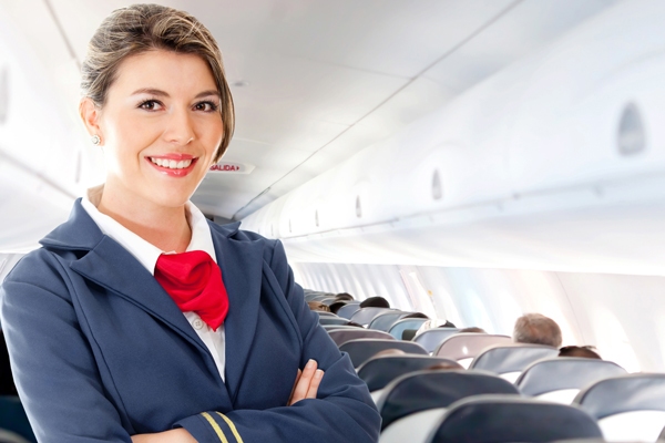 Smiling senior flight attendant standing inside an airplane, highlighting the importance of finding a financial advisor for career professionals in aviation.