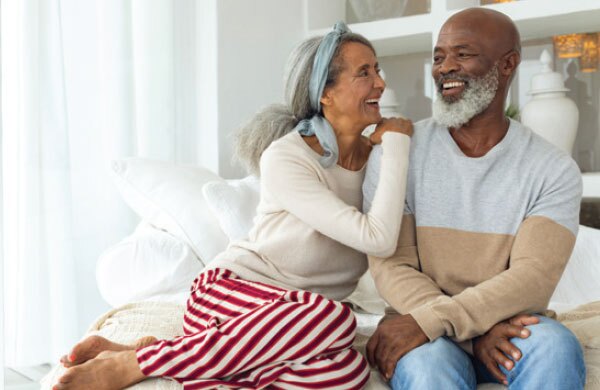 A cheerful senior couple relaxing together on a bed, reflecting commitment to a high standard of care and a reliable financial planning process.